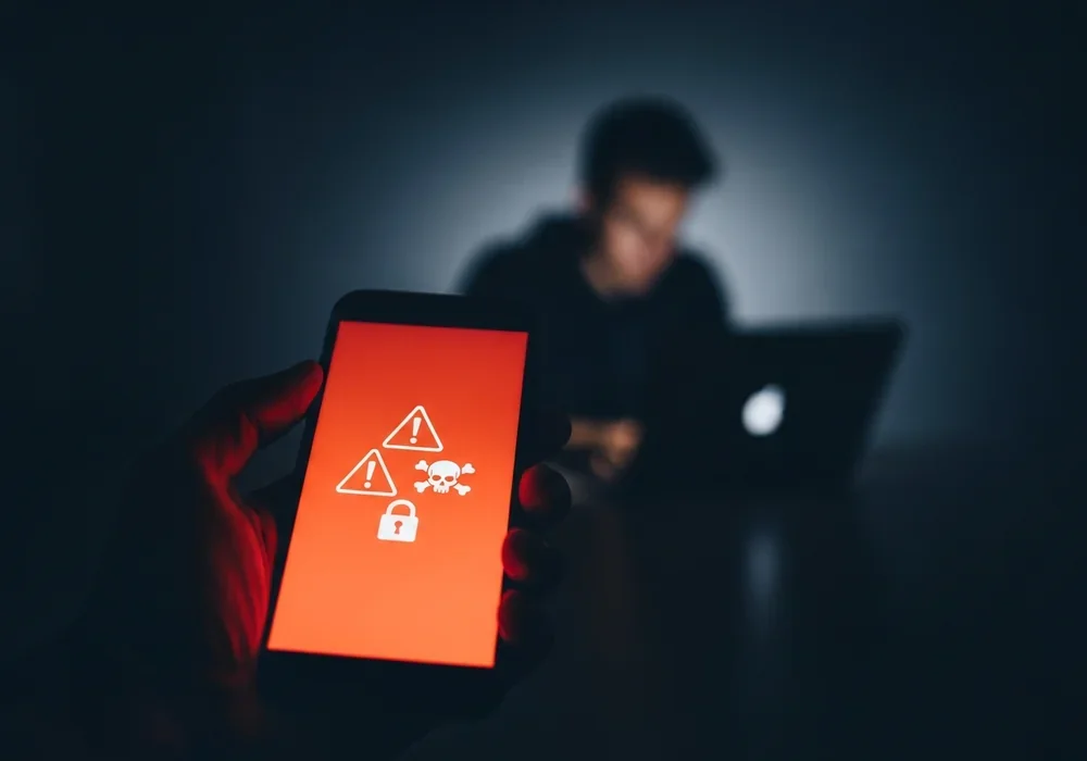 본문 이미지: A dramatic, cinematic close-up photo of a smartphone in a user's hand in a dimly lit room. The sc...